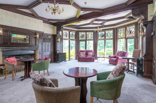 a living room with a fireplace and tables and chairs at Northop Hall Country House Hotel in Mold