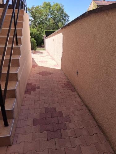 a brick sidewalk next to a wall with a staircase at Chambre d'hôtes Juline in Pouilly-les-Nonains