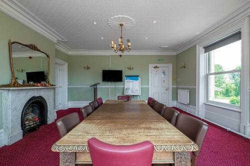a conference room with a table and chairs and a fireplace at Northop Hall Country House Hotel in Mold