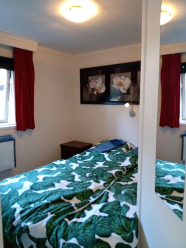 a bedroom with a bed with a green comforter at Jachtslot Chalet J8 in Doornspijk