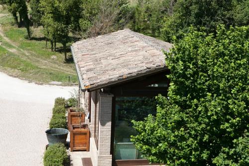 a house with a shingled roof and a bush at Re Artù Assisi Country Lifestyle in Assisi