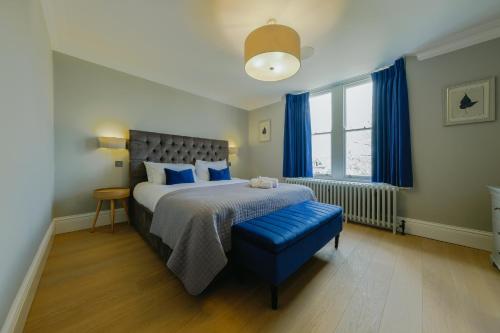 a bedroom with a bed and a blue ottoman at Elegant 2-Bed Luxury Apartment - Prime Location in Bristol