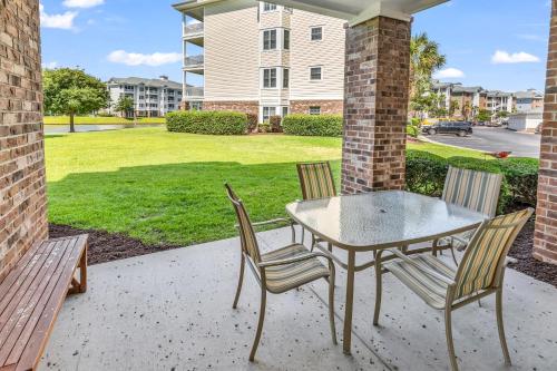 a patio with a table and chairs and a lawn at Myrtlewood by Monarch Rentals in Myrtle Beach
