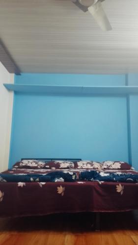 a bed in a room with a blue wall at आयुष्मान भव महाकाल लोक होमस्टै in Ujjain