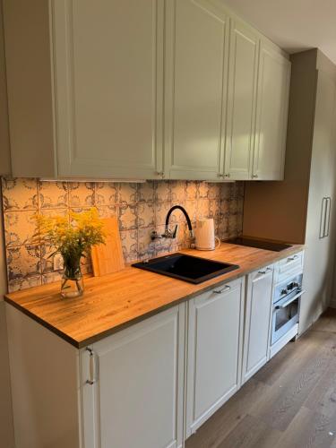 a kitchen with white cabinets and a wooden counter top at Folwark Hańcza in Wigry