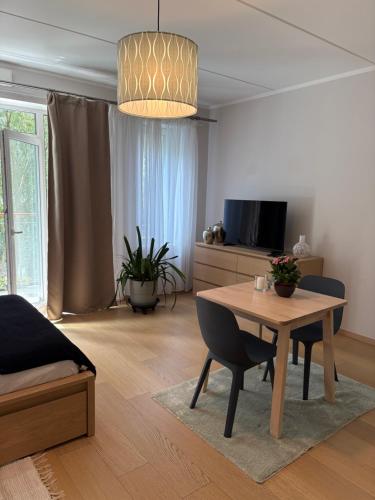 a living room with a table and a tv at Apartment Upeņu in Rīga