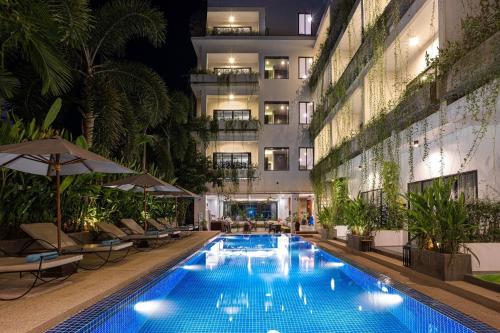 a swimming pool in front of a building at night at Grand Yard La Residence in Siem Reap