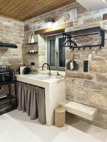 a kitchen with a sink and a stone wall at Chez moi in Chios