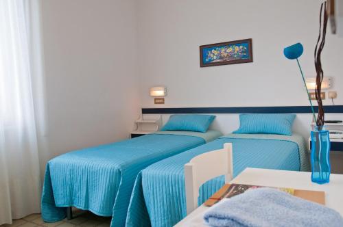 two beds in a room with blue sheets at Albergo La Rosetta in Chianciano Terme