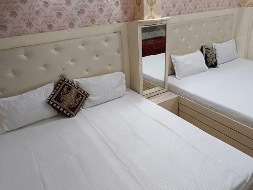 two beds in a small room with a mirror at Maa Vaishno Guest House in Varanasi