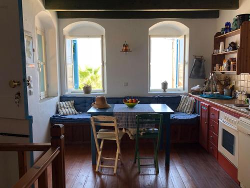 a kitchen with a table and chairs and two windows at Charming Villa in Symi in Symi