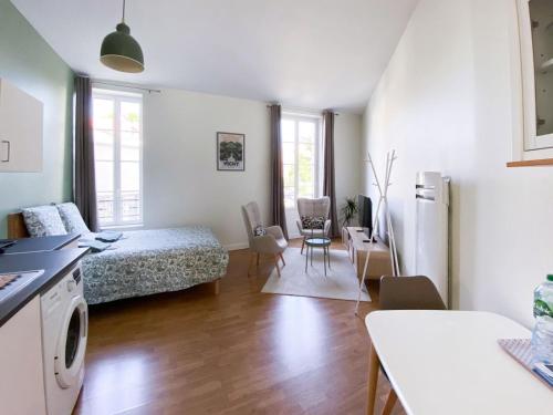 a bedroom with a bed and a kitchen with a table at Appartement Vichyssoise Edwige in Vichy
