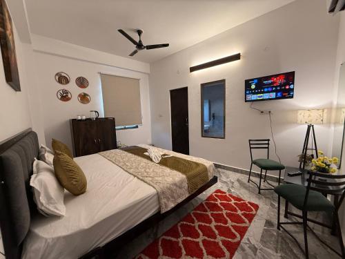 a bedroom with a bed and a tv on the wall at HOTEL ATULYAM STAYs PREMIUM in Prayagraj