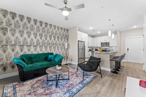 a living room with a green couch and a kitchen at Pinnacle Apartments W Amenties by Heavenly Homes in Orlando