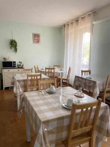 a dining room with tables and chairs and a kitchen at Résidence Hôtelière du Magnoac in Castelnau-Magnoac
