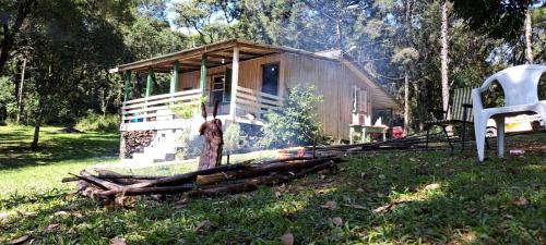 a small cabin in the woods with a chair in front of it at Cabana de pesca e lazer Represa Usina Mafra sc in Mafra