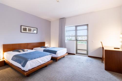 a hotel room with two beds and a window at Hotel La Fontaine in Esmoriz