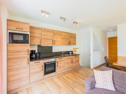 a kitchen with wooden cabinets and a couch at Chalet in Niedernsill near Ski Slopes in Niedernsill