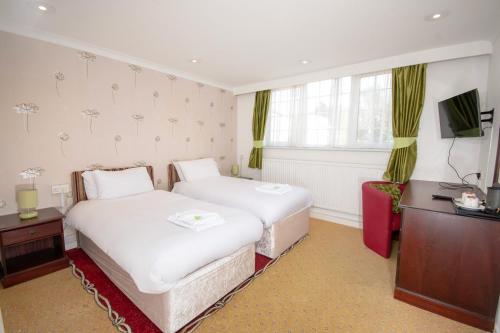a hotel room with two beds and a television at Northop Hall Country House Hotel in Mold