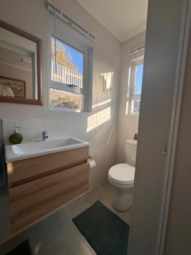 a bathroom with a toilet and a sink and a window at Cosy Cottage Greenside in Johannesburg