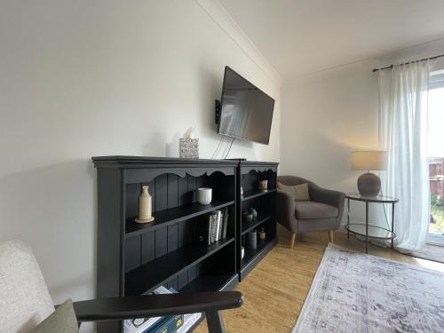 Una sala de estar con una estantería negra y una silla. en Greenfields House Ashford, en Kent