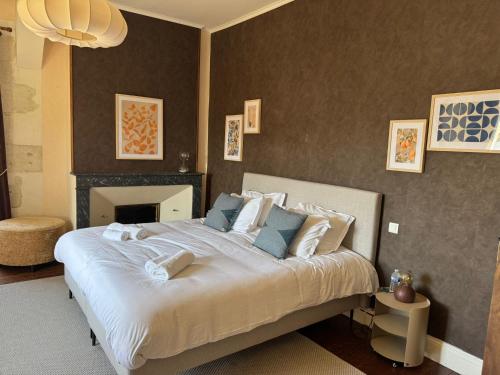 a bedroom with a large white bed with a fireplace at L'Amirauté sur Baïse in Saint-Jean-Poutge