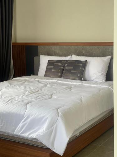 a bed with white sheets and pillows on it at Sun Executive Villas Sanur in Mantaak
