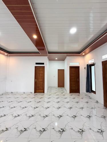 an empty room with a tile floor and wooden doors at Mehar Villa in Gunungpicung
