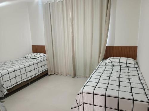 two twin beds in a room with a window at Refúgio com Lazer de Resort in Estância