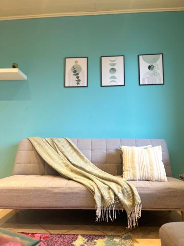a couch with a blanket on a blue wall at Cozy appartement in oberbarmen in Wuppertal