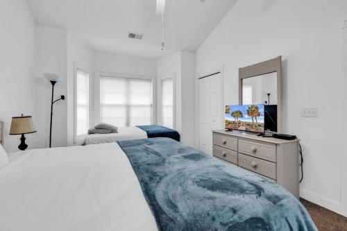 a white bedroom with a large bed and a television at Myrtlewood by Monarch Rentals in Myrtle Beach