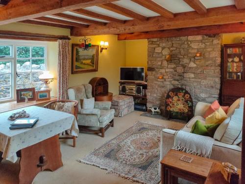 a living room with a stone fireplace and a table at Cow Cottage in Langford