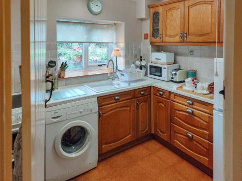 a kitchen with a washing machine and a sink at Cow Cottage in Langford