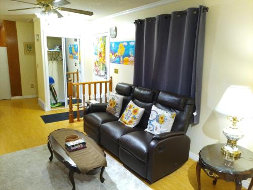 a living room with a leather couch and a table at Home Away from Home - Guest Suite 1 in Red Deer