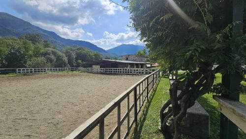 a fence in front of a house with mountains in the background at Agriturismo dei Laghetti in Porto Valtravaglia