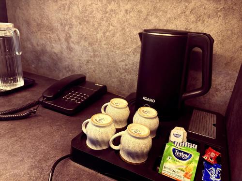 a counter with a coffee maker and coffee cups and a telephone at Rudraksha Guest House in Varanasi