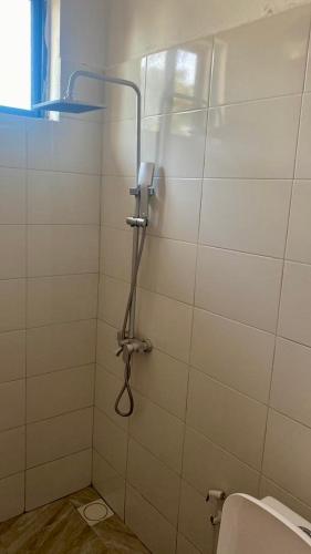 a shower in a white tiled bathroom with a toilet at Villa Katerina Kendwa in Kendwa