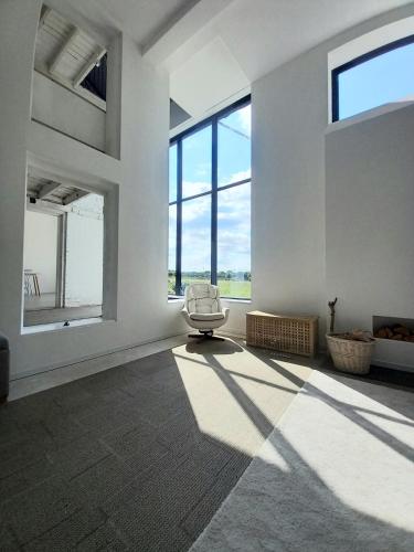 a white room with a chair and large windows at The Dutch Barn in Maidstone