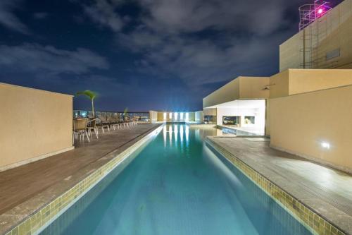 a swimming pool with blue water at night at Flat no Prime Promenade Itaboraí in Itaboraí