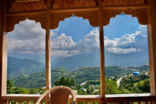 a chair sitting on a porch with a view of mountains at Echoes of Nirvana in Theog