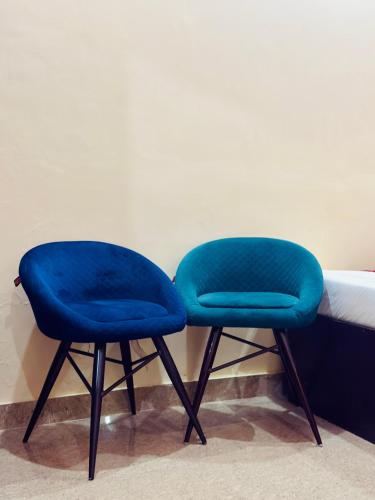 two blue chairs sitting next to a bed at Hotel Chandra Dreams in Varanasi