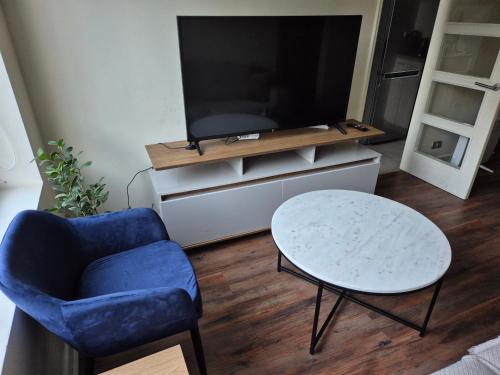 a living room with a tv and a blue chair and a table at Cómodo y acogedor departamento in Osorno