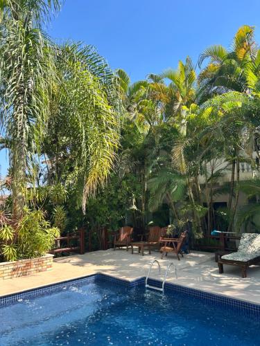 a swimming pool next to a resort with palm trees at Arco Íris Pousada in Ilha Comprida