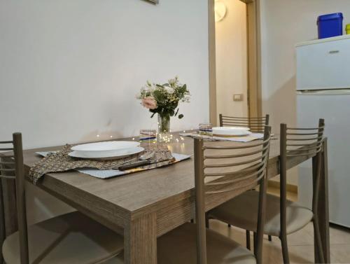 a dining room table with plates and a vase of flowers at Home AGM in Pozzallo