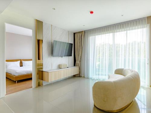 a living room with a couch and a tv and a bed at 2BR Luxury Condo The City Phuket in Ban Ket Ho