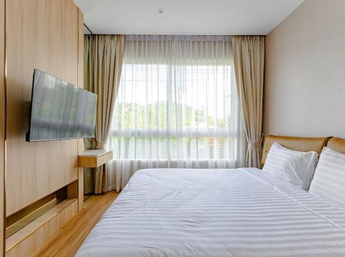 a bedroom with a large bed and a television at 2BR Luxury Condo The City Phuket in Ban Ket Ho