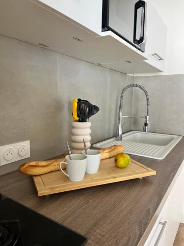 un bancone della cucina con un tagliere con due tazze e pane di Bungalow Corossol a Deshaies
