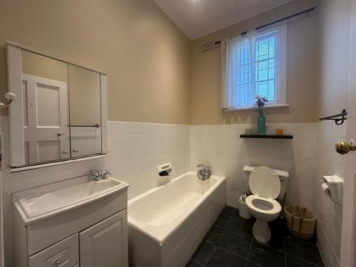 a bathroom with a tub and a toilet and a sink at Glenwood Cottage 5km from beach, Art gallery, with garden and pool in Durban