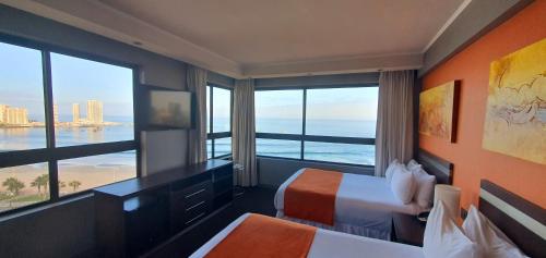 a hotel room with two beds and a view of the ocean at Gran Cavancha Suite in Iquique