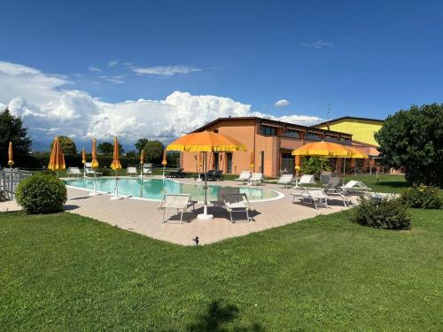 a swimming pool with chairs and umbrellas and a building at Agriturismo Aver in Villafranca di Verona